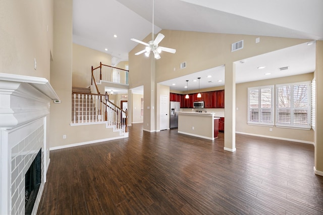 unfurnished living room featuring dark wood finished floors, visible vents, a fireplace, and stairway