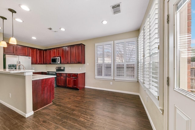 kitchen with stainless steel appliances, dark brown cabinets, dark wood-style flooring, and visible vents