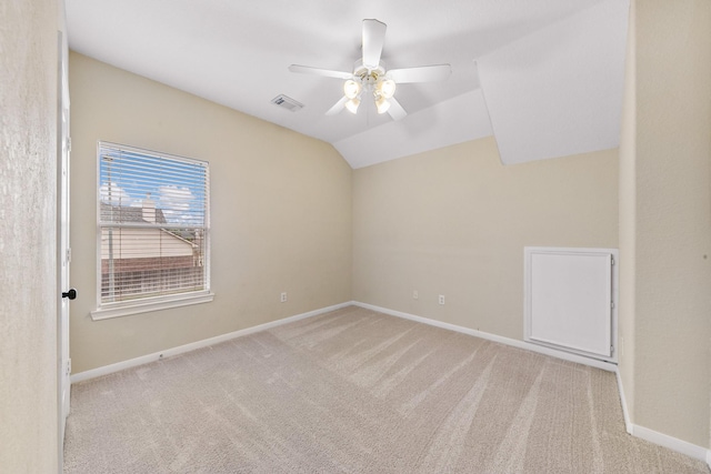 spare room featuring lofted ceiling, ceiling fan, carpet floors, visible vents, and baseboards