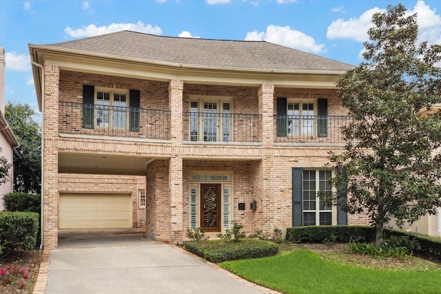 view of front of property featuring a balcony, roof with shingles, concrete driveway, and brick siding