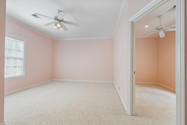 carpeted spare room with visible vents, crown molding, and ceiling fan