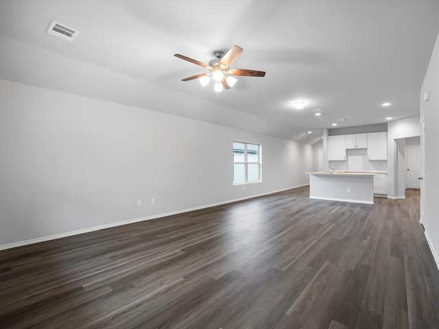 unfurnished living room with baseboards, visible vents, dark wood finished floors, and a ceiling fan