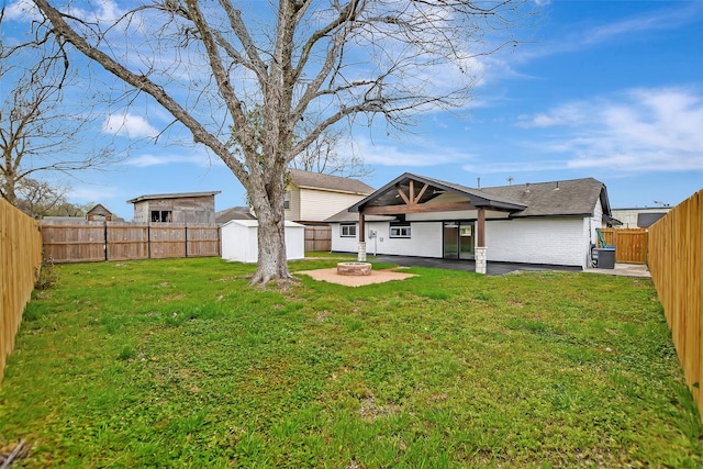 rear view of house featuring an outdoor fire pit, a fenced backyard, a storage unit, and a patio