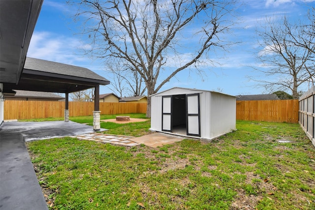 view of yard featuring an outdoor fire pit, a fenced backyard, an outdoor structure, a storage unit, and a patio area