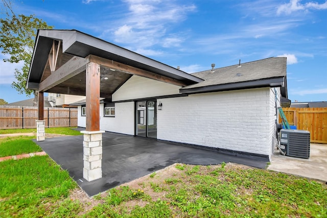 back of property with brick siding, central air condition unit, a patio area, fence, and a carport