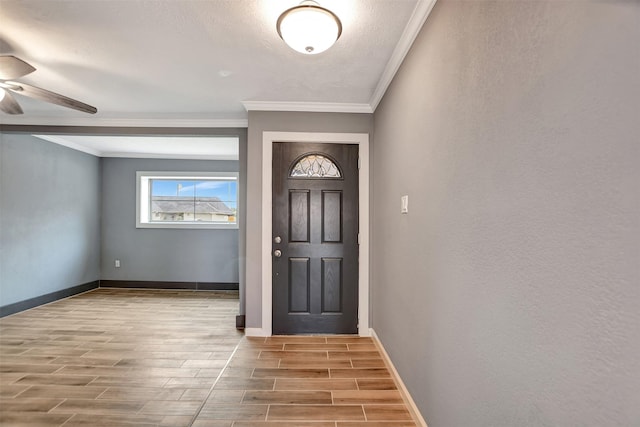 foyer entrance featuring crown molding, ceiling fan, baseboards, and wood tiled floor