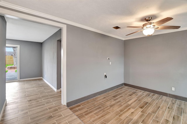 spare room with ornamental molding, wood tiled floor, baseboards, and a ceiling fan