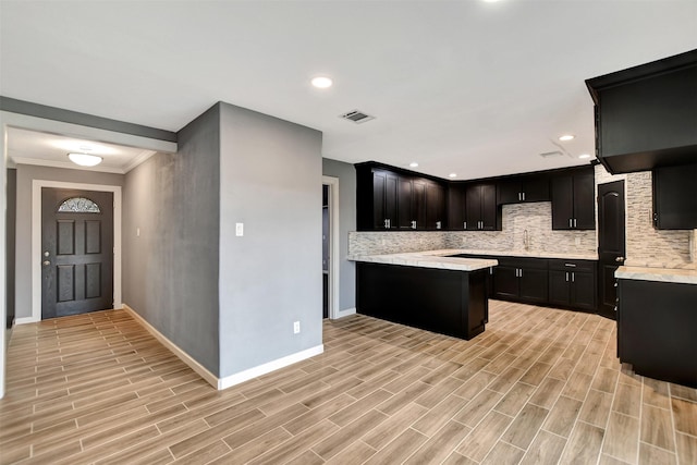 kitchen featuring wood finish floors, a sink, visible vents, light countertops, and backsplash