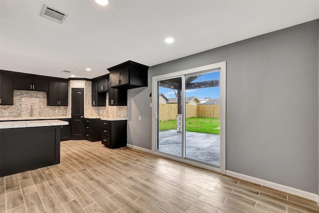 kitchen featuring wood finish floors, visible vents, baseboards, light countertops, and tasteful backsplash