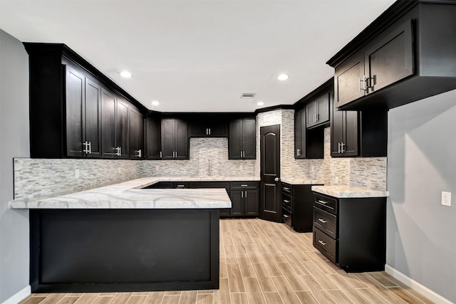 kitchen featuring visible vents, baseboards, decorative backsplash, a peninsula, and wood finish floors