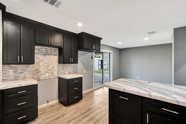 kitchen featuring wood finish floors, visible vents, light countertops, dark cabinetry, and tasteful backsplash