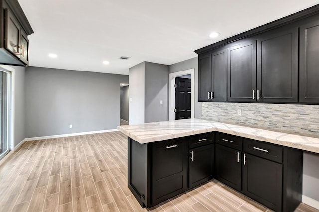 kitchen featuring light stone countertops, wood tiled floor, visible vents, and backsplash