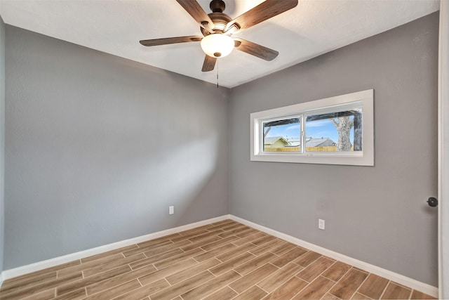 empty room featuring wood tiled floor, baseboards, and ceiling fan