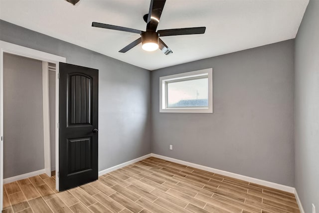 unfurnished bedroom with wood finish floors, ceiling fan, and baseboards