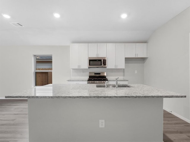 kitchen featuring a sink, visible vents, white cabinets, appliances with stainless steel finishes, and an island with sink