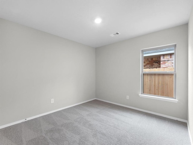 unfurnished room with carpet floors, visible vents, and baseboards