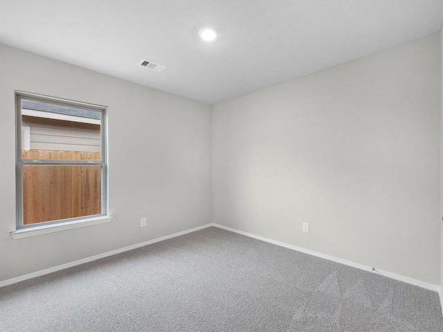 empty room featuring carpet floors, visible vents, and baseboards