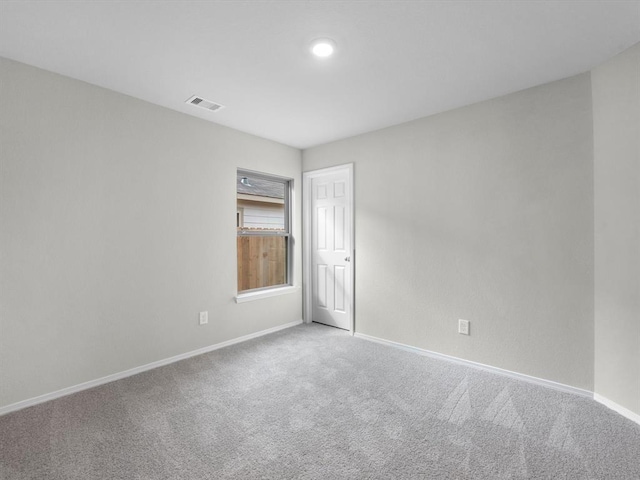 unfurnished room with carpet, visible vents, and baseboards