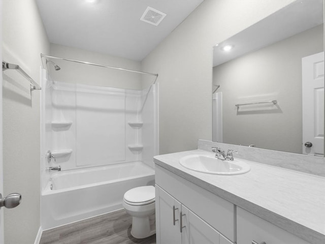 bathroom with visible vents, toilet, wood finished floors, vanity, and shower / bathing tub combination