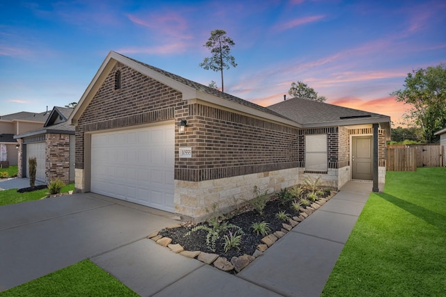 single story home with a garage, a front yard, stone siding, and brick siding