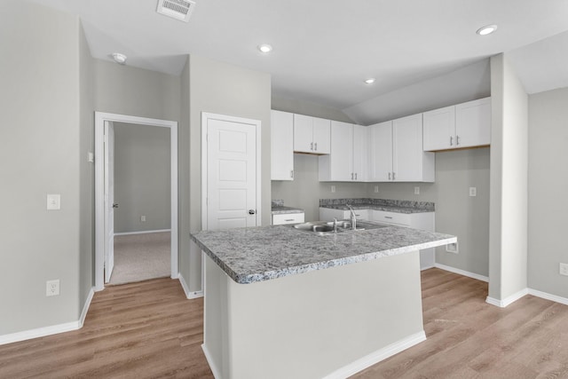 kitchen with white cabinetry, visible vents, light wood-style flooring, and a sink