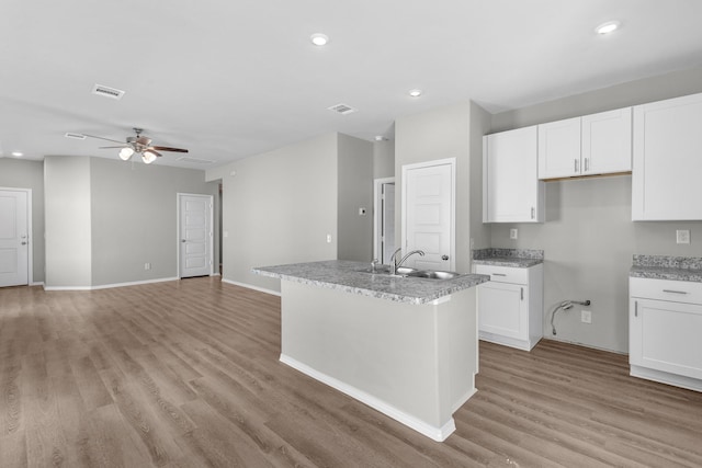 kitchen with white cabinets, visible vents, a sink, and light wood-style flooring