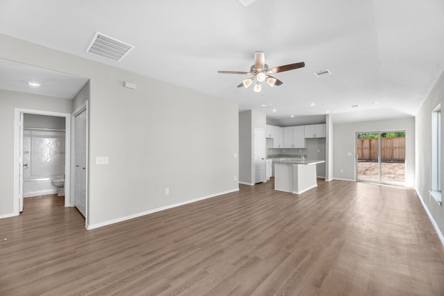 unfurnished living room featuring visible vents, baseboards, and wood finished floors