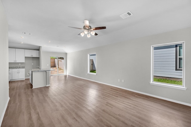 unfurnished living room featuring baseboards, visible vents, and light wood-style flooring