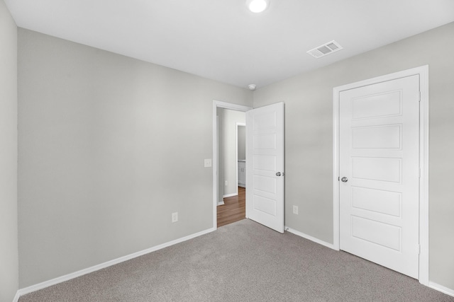 unfurnished bedroom featuring carpet, visible vents, and baseboards