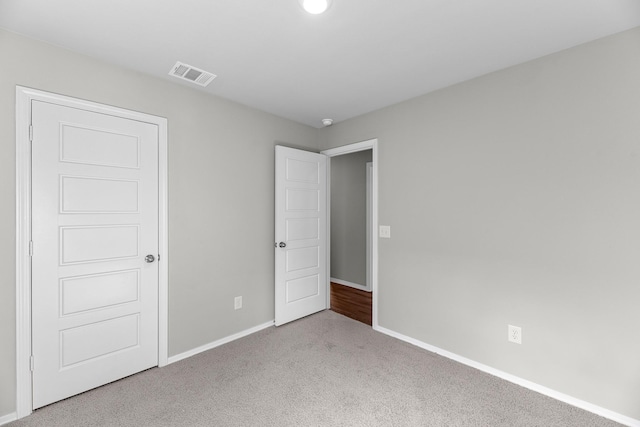 unfurnished bedroom with carpet floors, baseboards, and visible vents