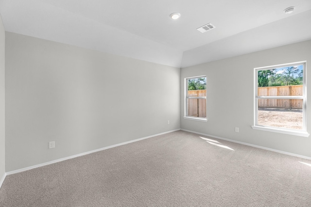 unfurnished room featuring carpet floors, visible vents, vaulted ceiling, and baseboards