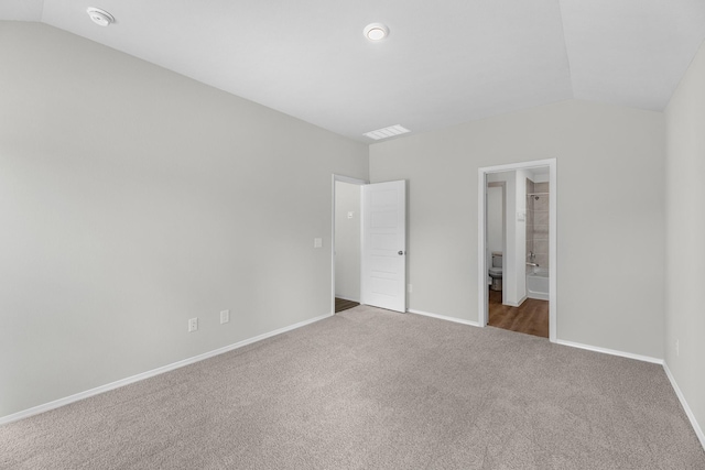 unfurnished bedroom with lofted ceiling, ensuite bathroom, carpet flooring, visible vents, and baseboards