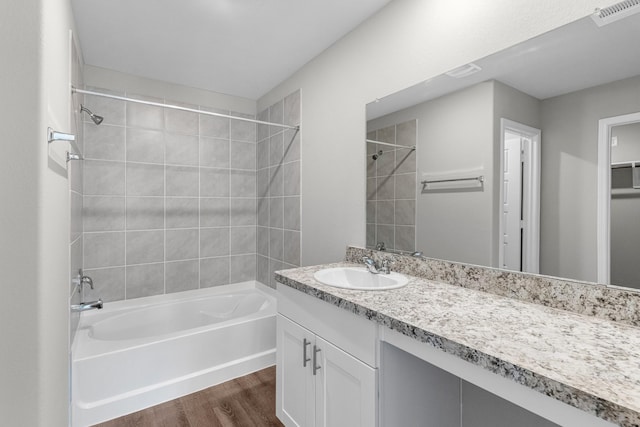 bathroom featuring vanity, visible vents, wood finished floors, and bathing tub / shower combination