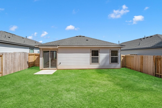 rear view of house featuring a fenced backyard, a lawn, and roof with shingles