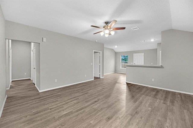 unfurnished living room with vaulted ceiling, wood finished floors, visible vents, and a ceiling fan