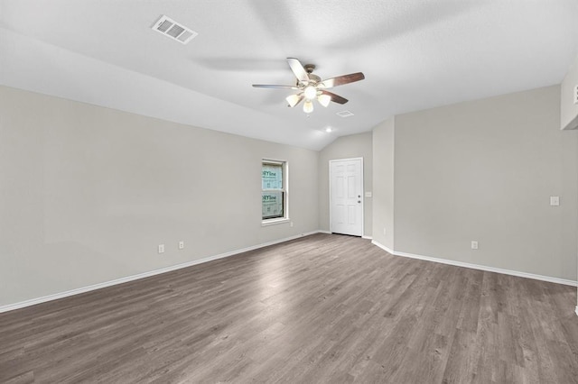 unfurnished room featuring lofted ceiling, ceiling fan, wood finished floors, visible vents, and baseboards