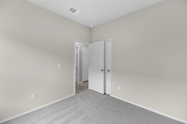 spare room with carpet floors, baseboards, and visible vents