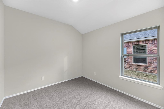 carpeted empty room with lofted ceiling, a healthy amount of sunlight, and baseboards