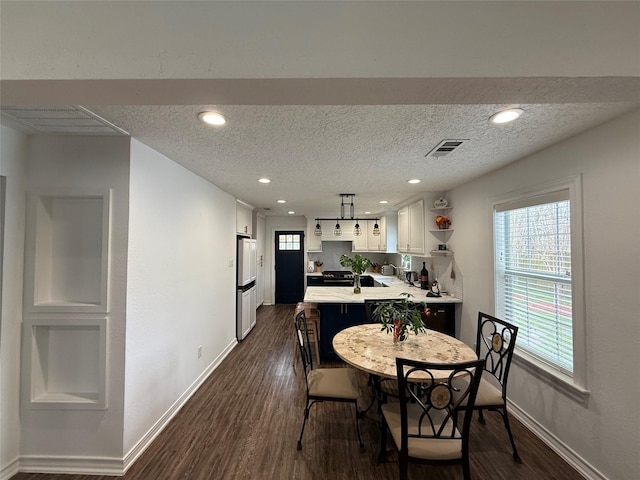 dining room featuring baseboards, visible vents, dark wood-style flooring, and a wealth of natural light