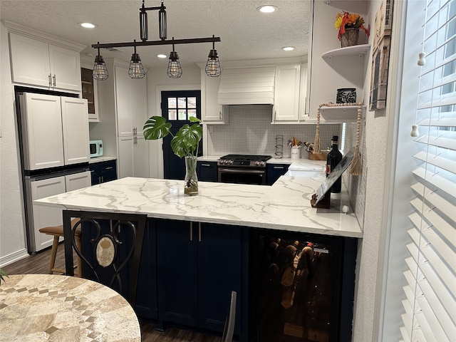 kitchen with custom range hood, a peninsula, stainless steel gas range, paneled built in refrigerator, and open shelves