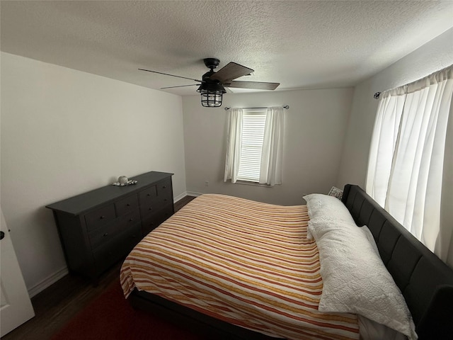 bedroom featuring a textured ceiling, dark wood finished floors, a ceiling fan, and baseboards