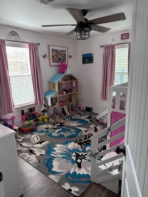 game room with ceiling fan, a textured ceiling, and wood finished floors