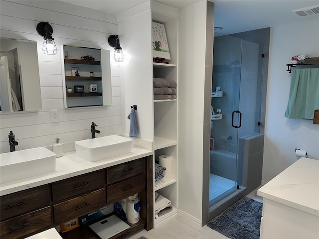 full bath featuring double vanity, a shower stall, visible vents, and a sink