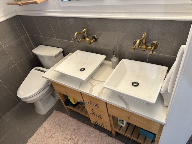 bathroom with toilet, tile patterned floors, tile walls, and vanity