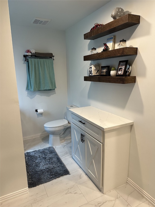 half bathroom featuring toilet, marble finish floor, visible vents, and baseboards