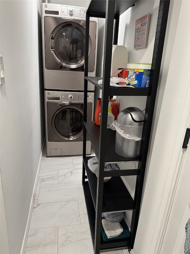 clothes washing area featuring marble finish floor, baseboards, laundry area, and stacked washer / dryer