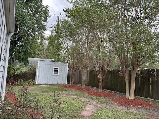 view of yard with a storage shed, a fenced backyard, and an outbuilding