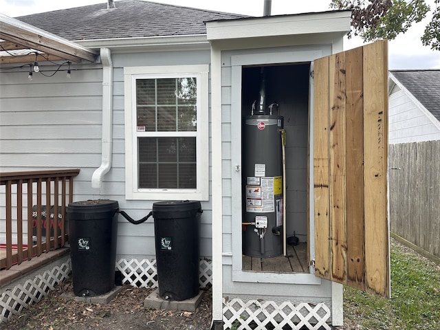 exterior space featuring gutters, a downspout, fence, water heater, and roof with shingles