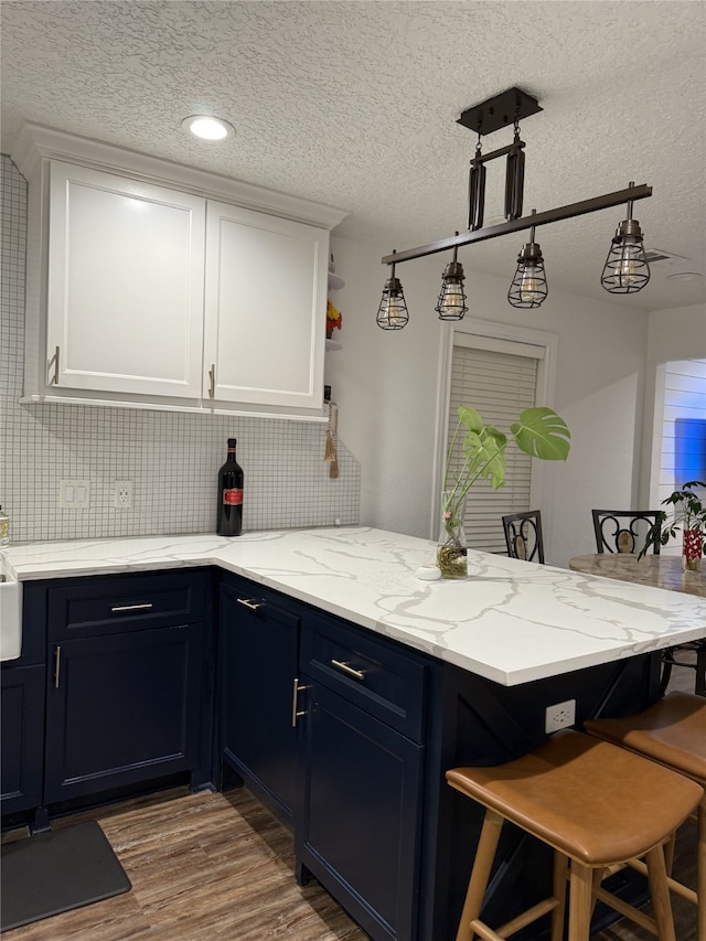 kitchen with a breakfast bar area, open shelves, white cabinetry, wood finished floors, and a peninsula