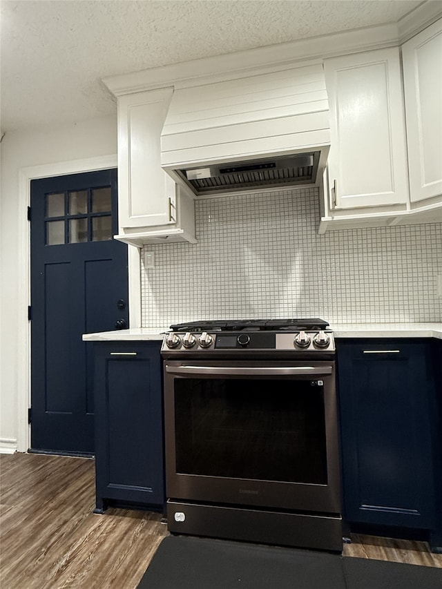 kitchen with stainless steel gas range oven, custom range hood, light countertops, and dark wood-style flooring